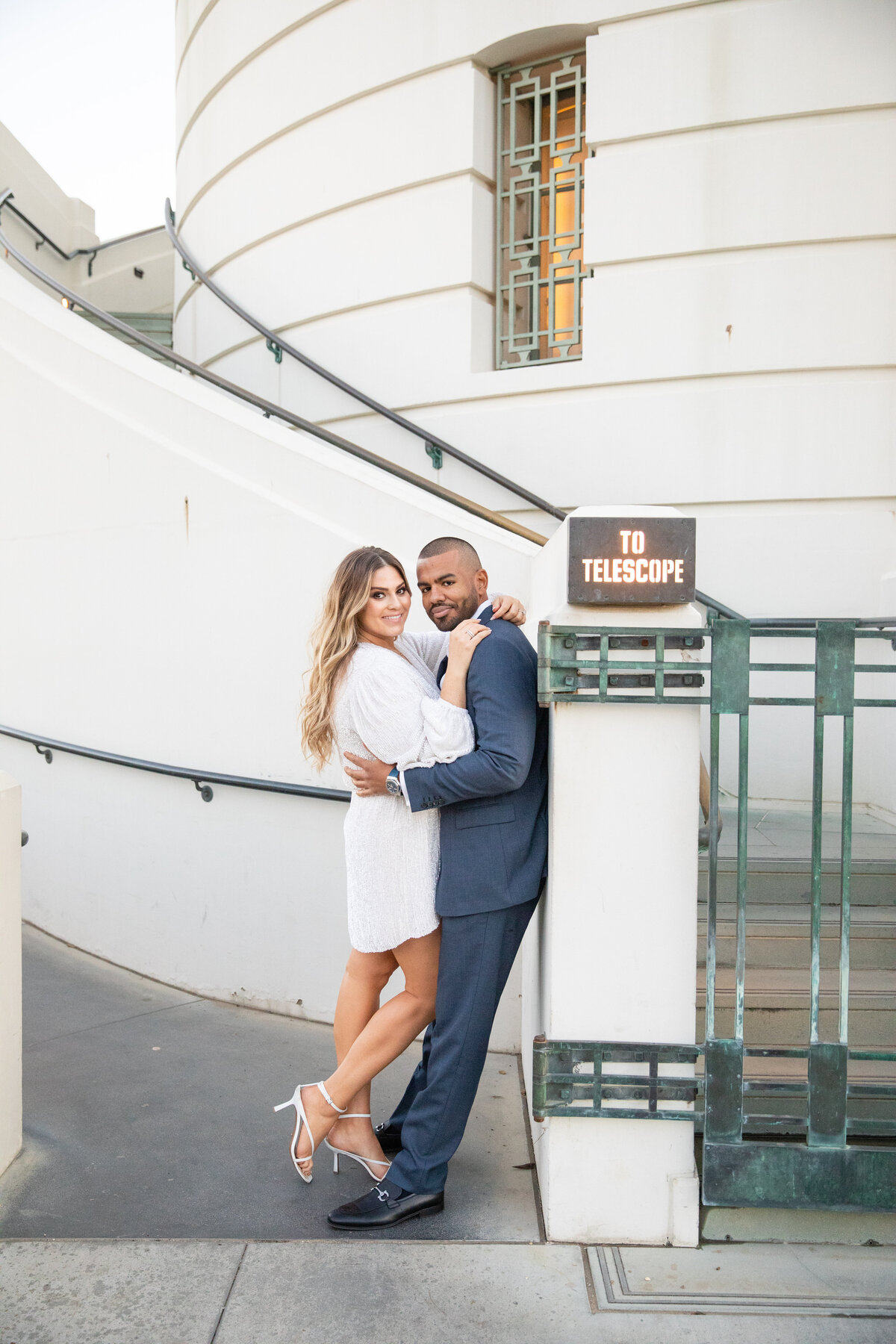 Couple leaning next to a telescope sign
