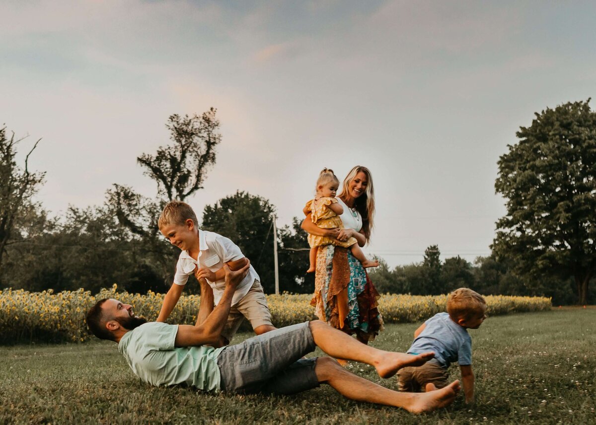 A Pittsburgh family photographer captures a family playing in a field at sunset.