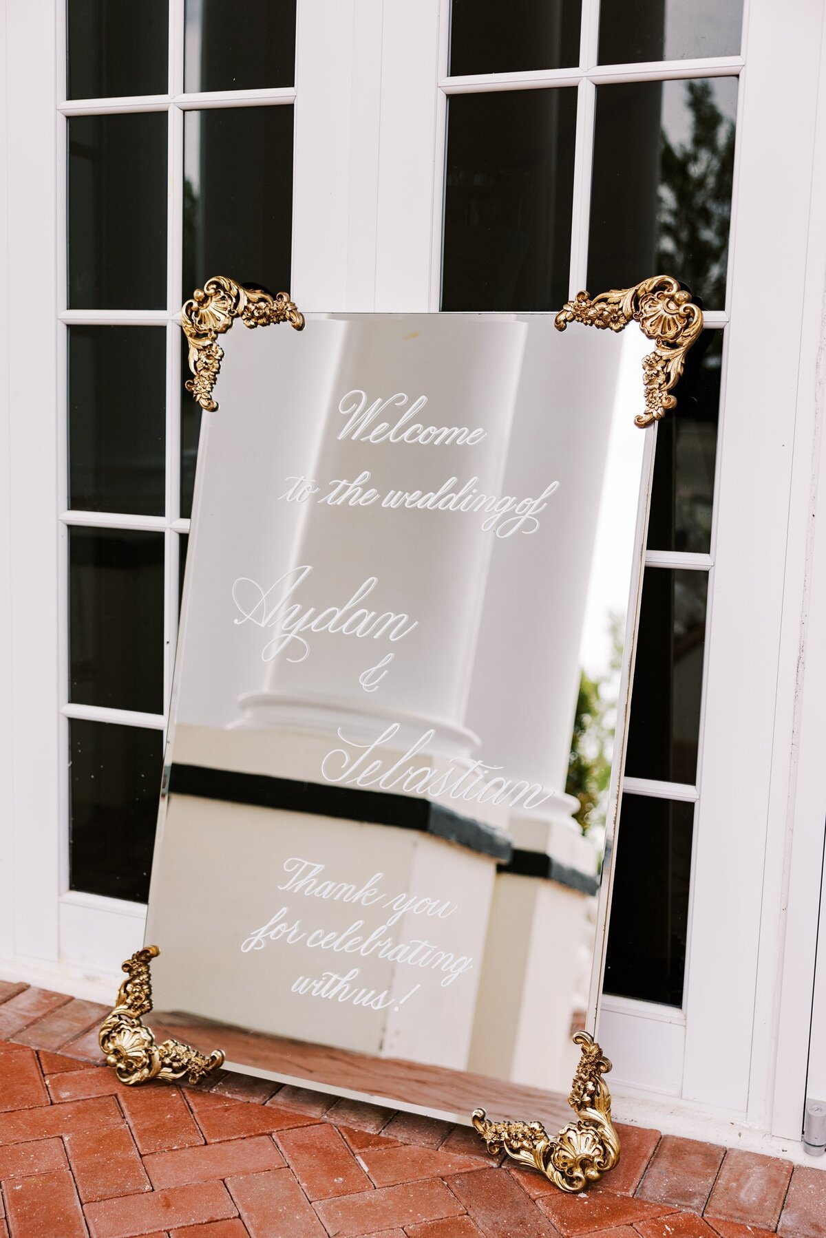 Large gold mirror with ornate ornaments on the corners with calligraphy for welcome sign