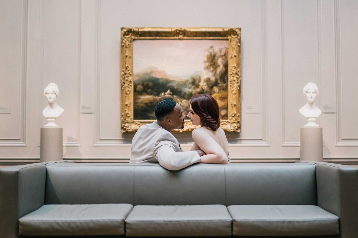 couple sitting on a sofa in front of a oil painting in the national gallery of art in Washington D.C.