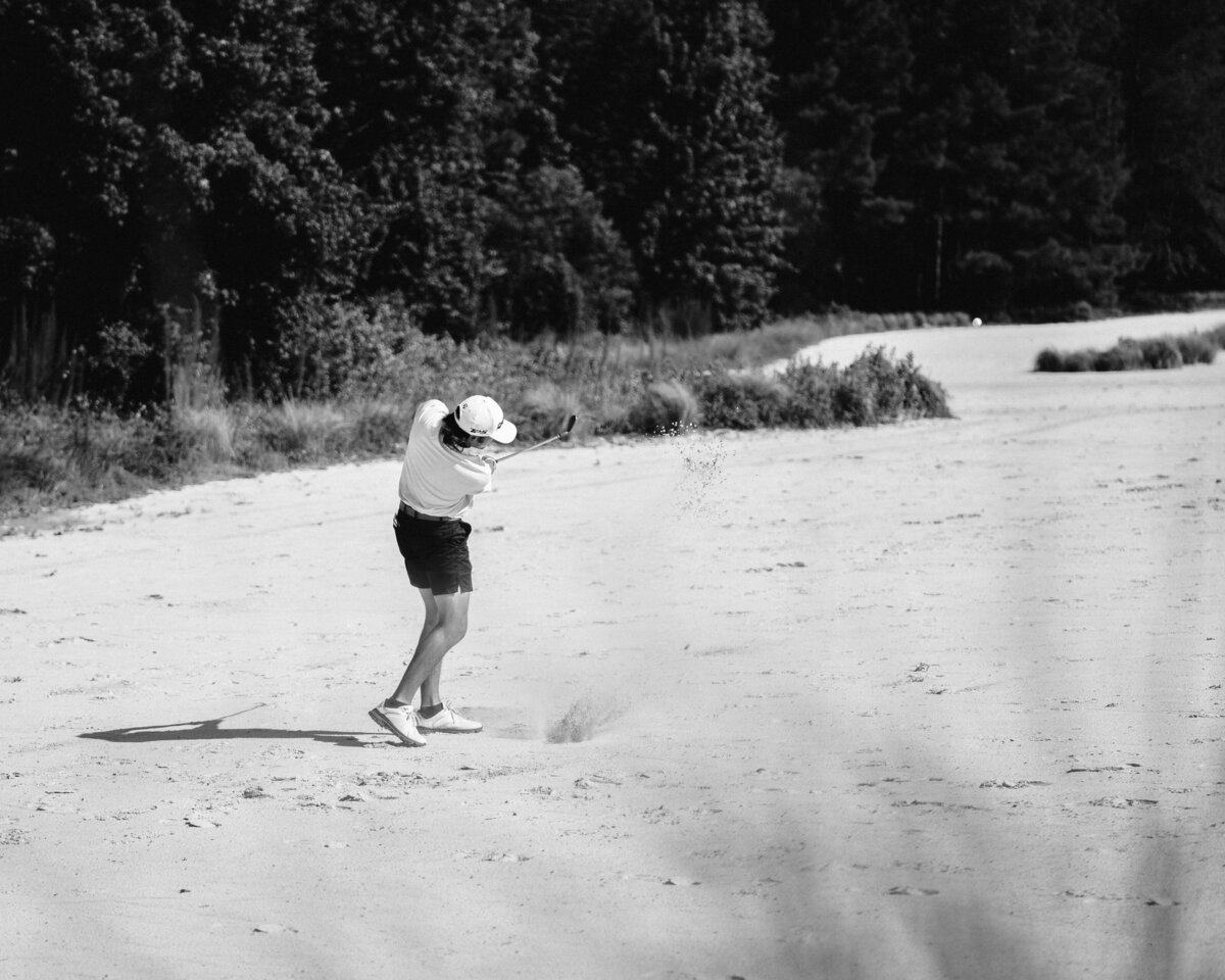 High-Key Black and White photo of golfer hitting a ball out of a large sand trap at Tobacco Road in Sanford, NC.