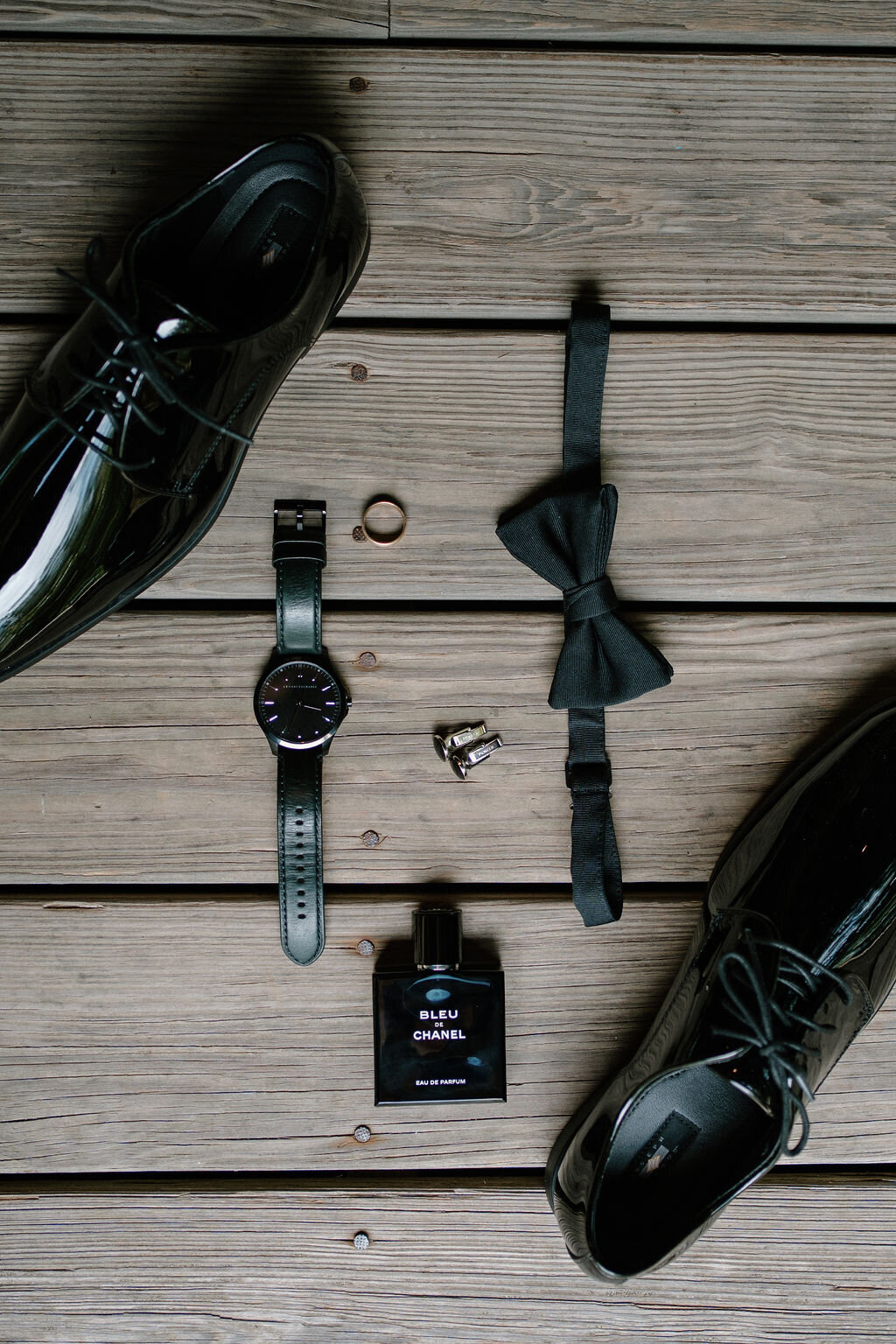 a flat lay image of a groom's wedding day style items shoes wedding ring and watch on the porch boards of the Willowbrook wedding venue