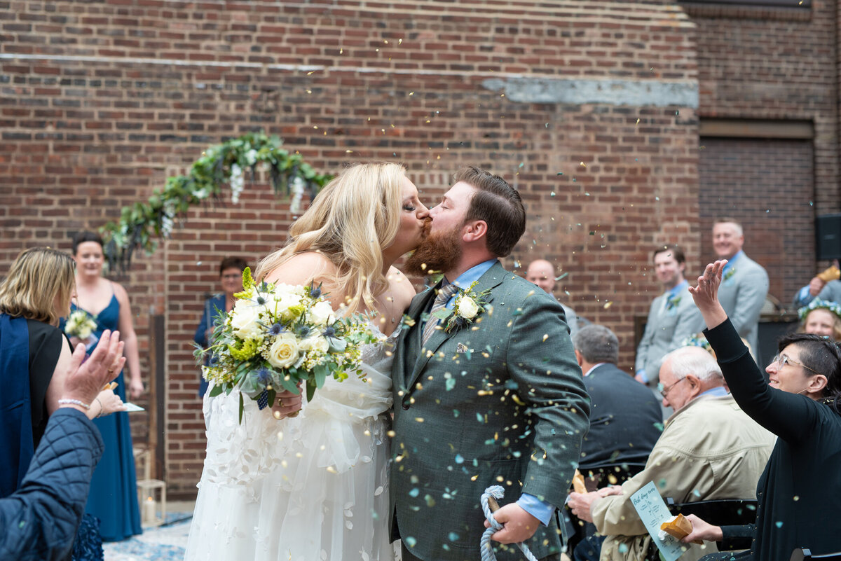 Bride and groom kissing in aisle at their spring Minnesota wedding