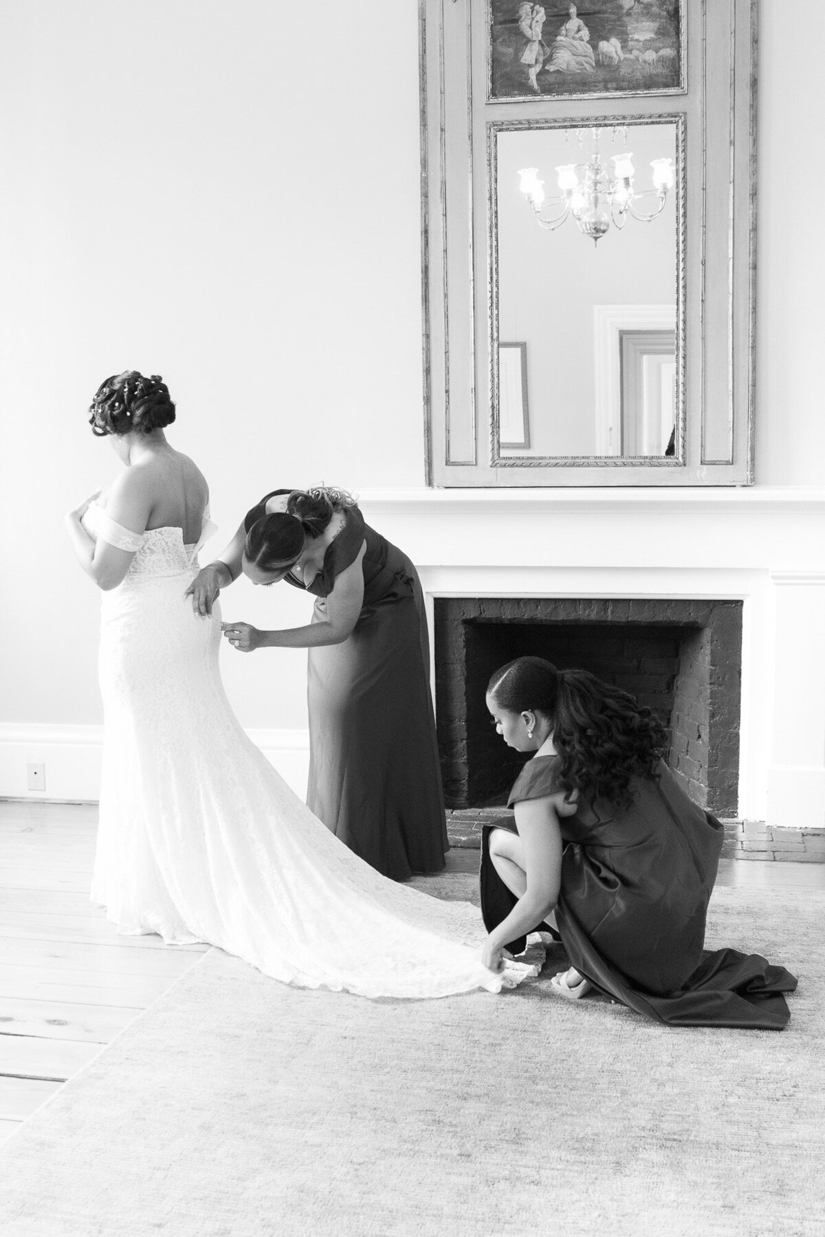 Black bride and two bridesmaids getting dressed in front of a fireplace at SC Lace House