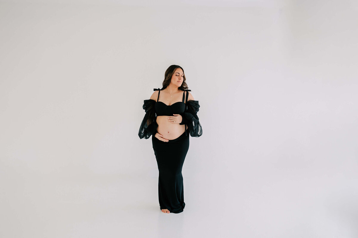 maternity photo of mom holding bare baby bump closing eyes captured by Joplin Mo maternity photographer Jessica Kennedy of The XO Photography
