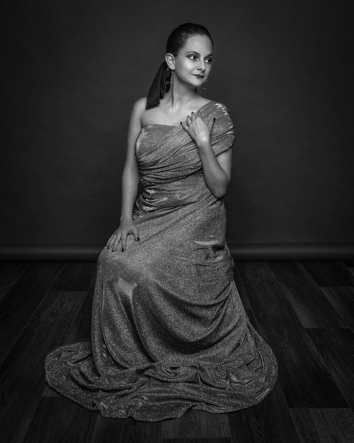 woman in elegant flowing dress looking sideways while sitting in studio