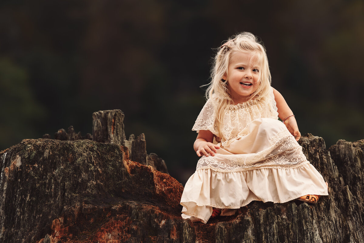 young-girl-laughing-on-stump