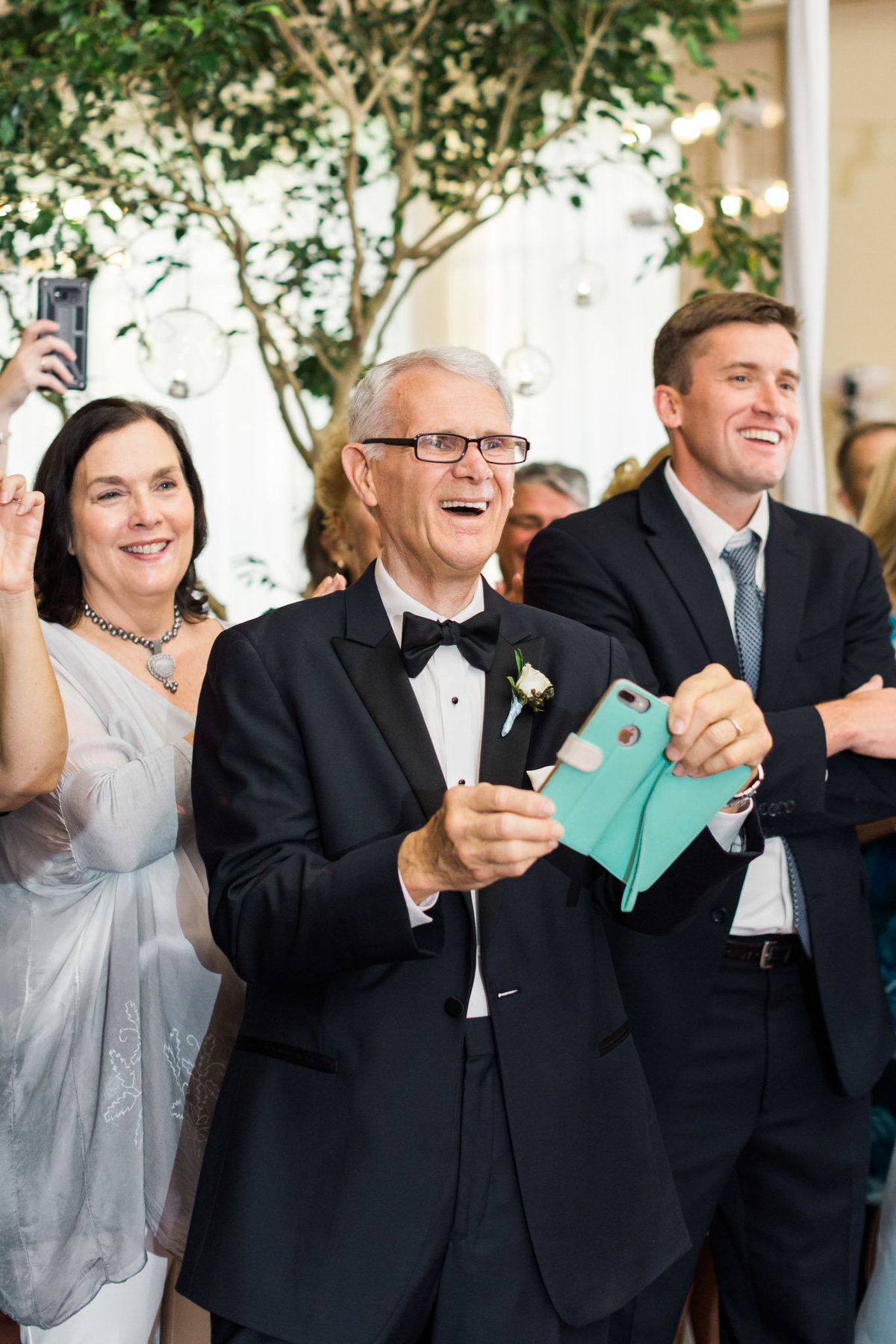 The father of the groom stood in awe as he videoed his wife doing a choreographed surprise dance planned just moments prior. Photo by luxury destination wedding photographer Rebecca Cerasani.