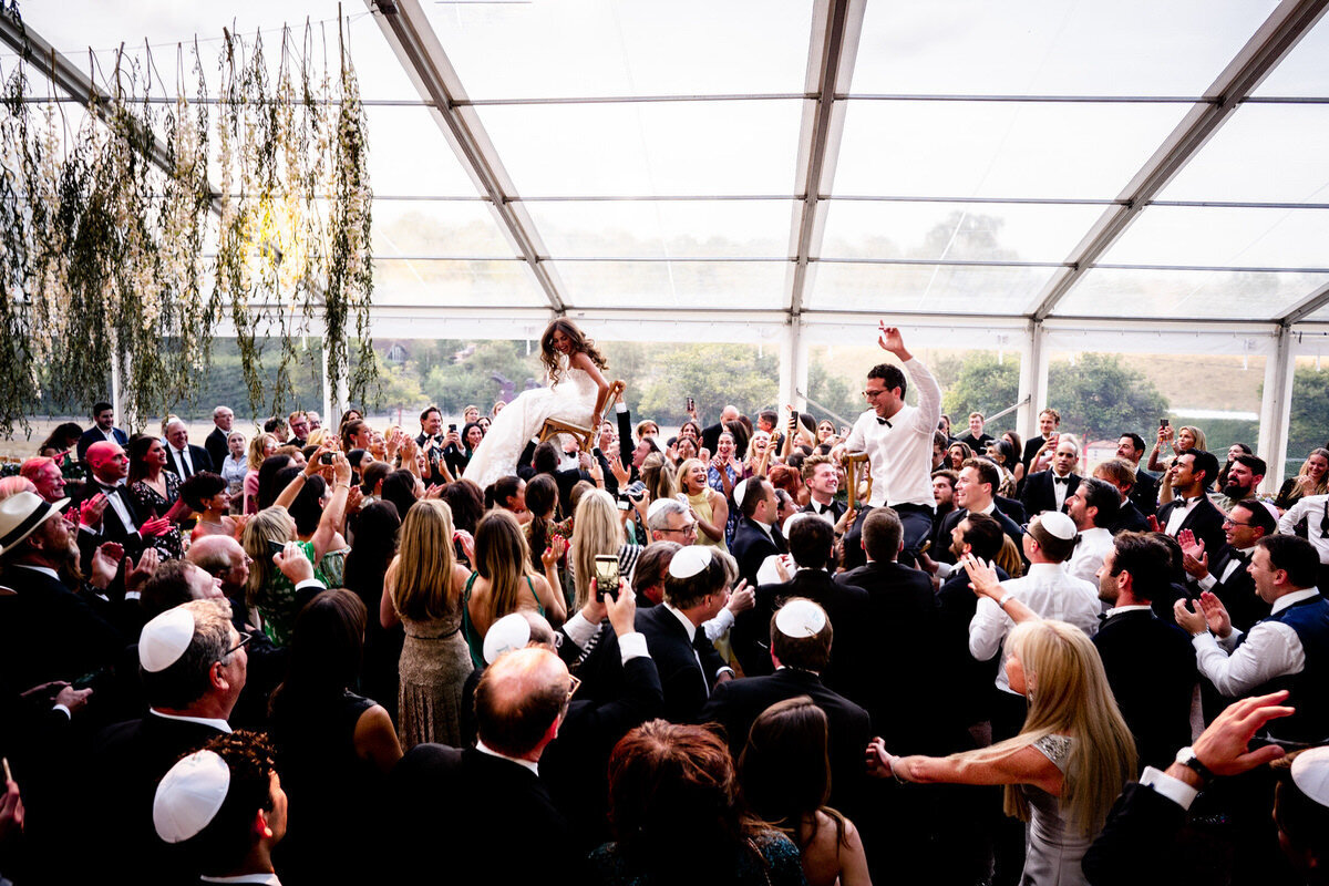 Jewish couple being thrown in the air on chairs during the wedding reception party near Bristol