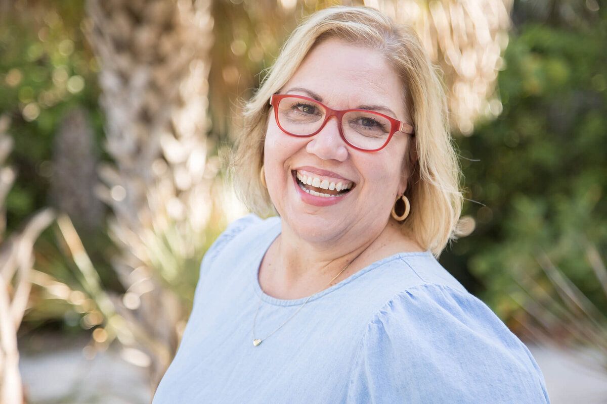 Bright and happy woman earing blue dress and red glasses smiling