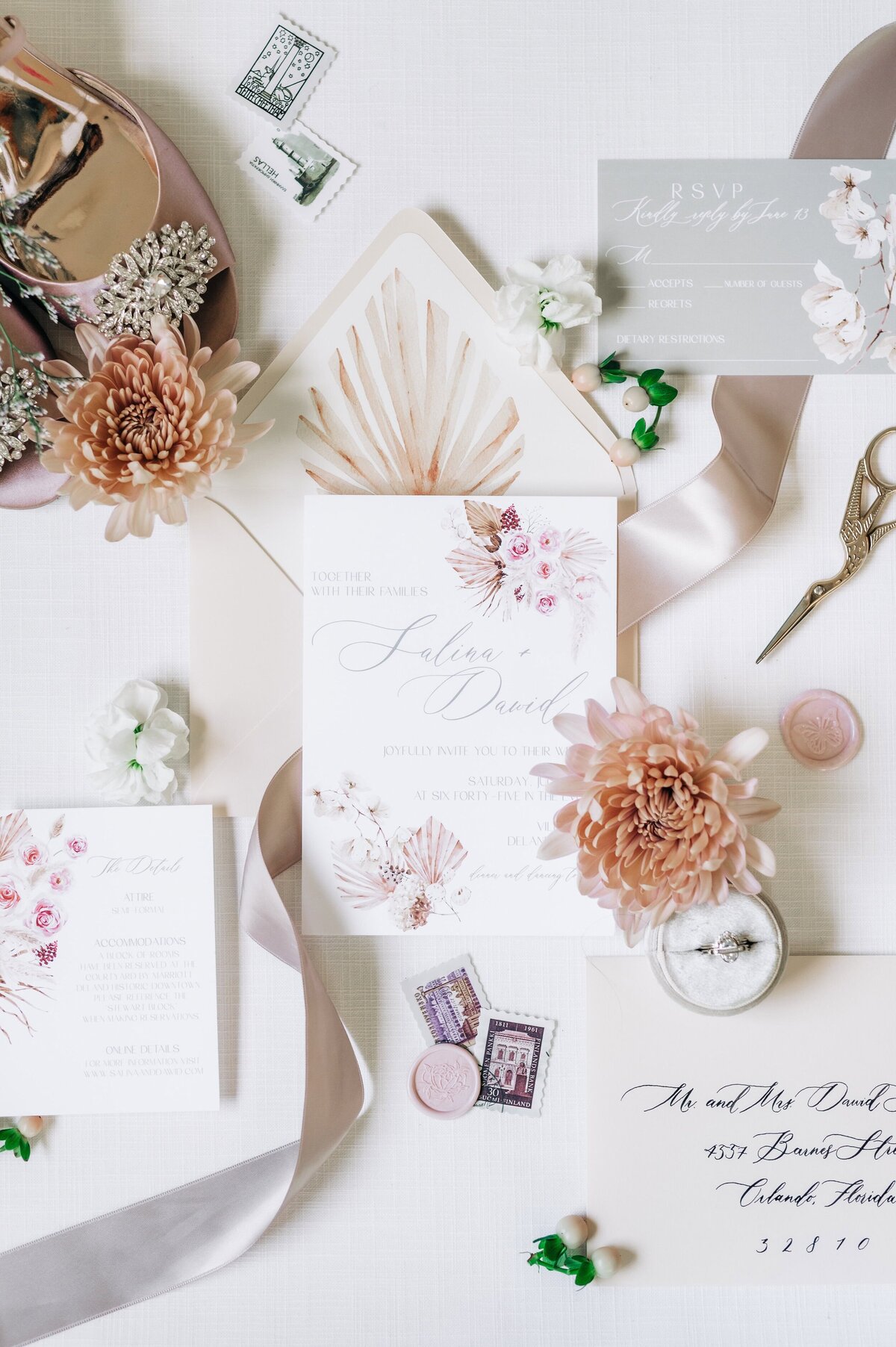 Flat lay of a floral wedding invitation suite with blush and beige tones