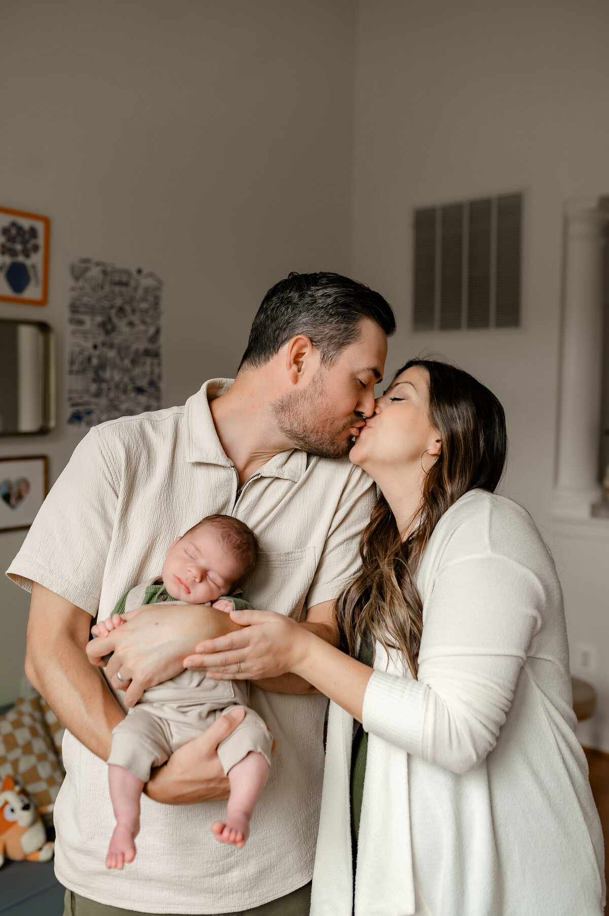 Mother and father hold sleeping baby while kissing each other in Ijamsville MD