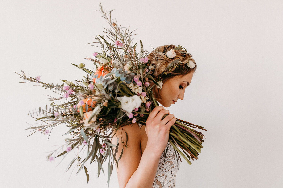 bride holding large bouquet of flowers over shoulder
