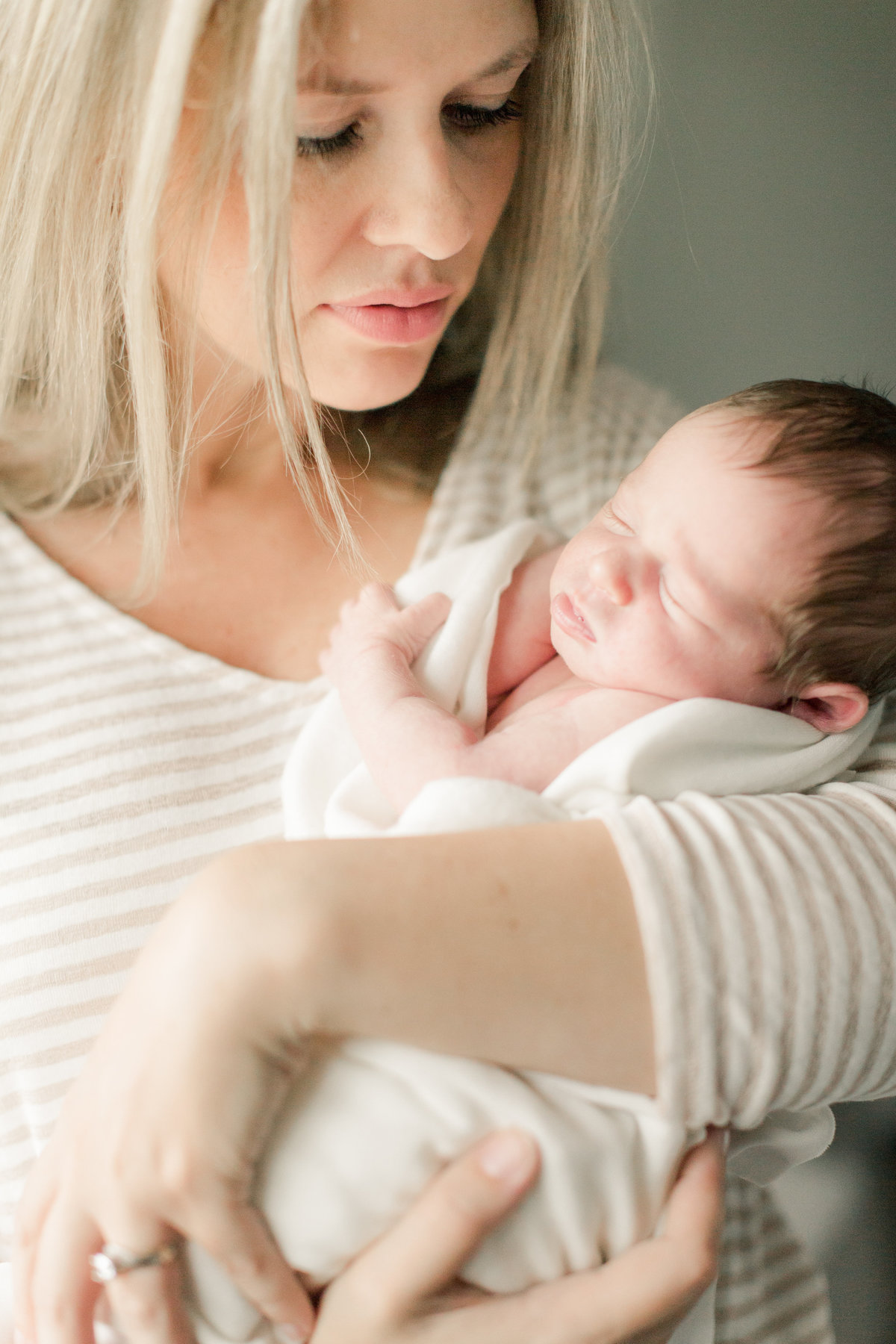 mom holds newborn baby girl in arms and looks adoringly in nursery of home rochester minnesota