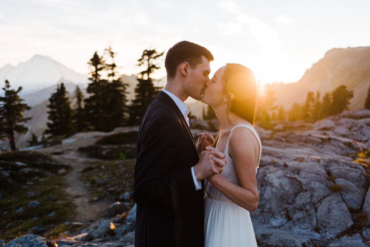 A n eloping couple kissing at Artist Point with the sunset glowing behind them. 