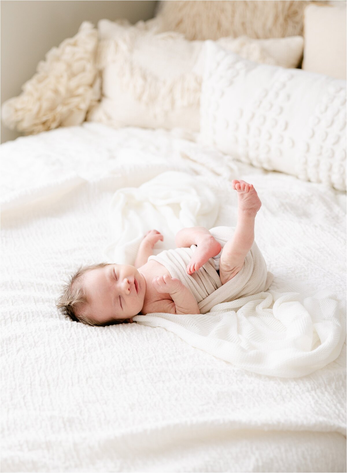 baby boy stretching on bed during indianapolis newborn photography session