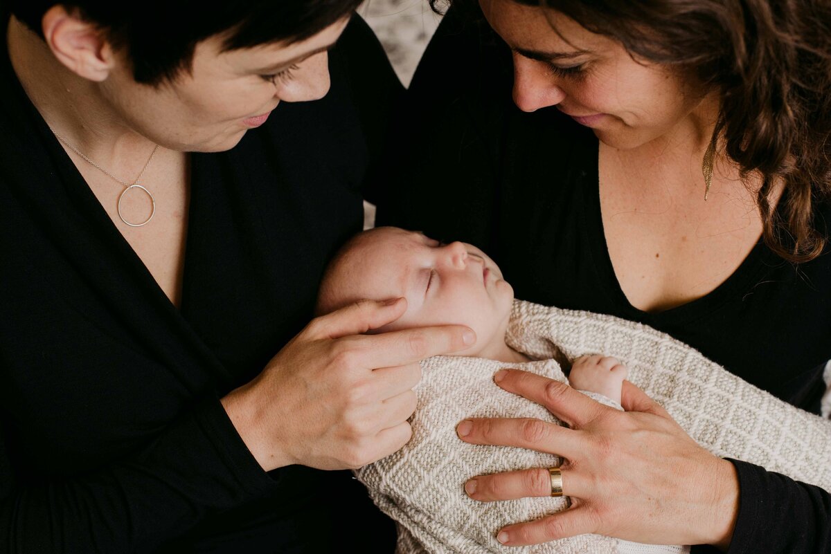 same sex moms with newborn baby wrapped in blanket