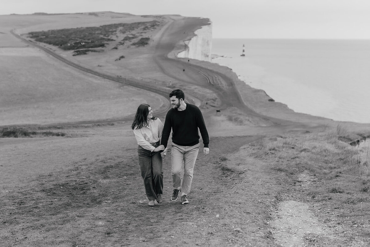 Couple walk hand in hand along the cliffside at Beachy Head Eastbourne