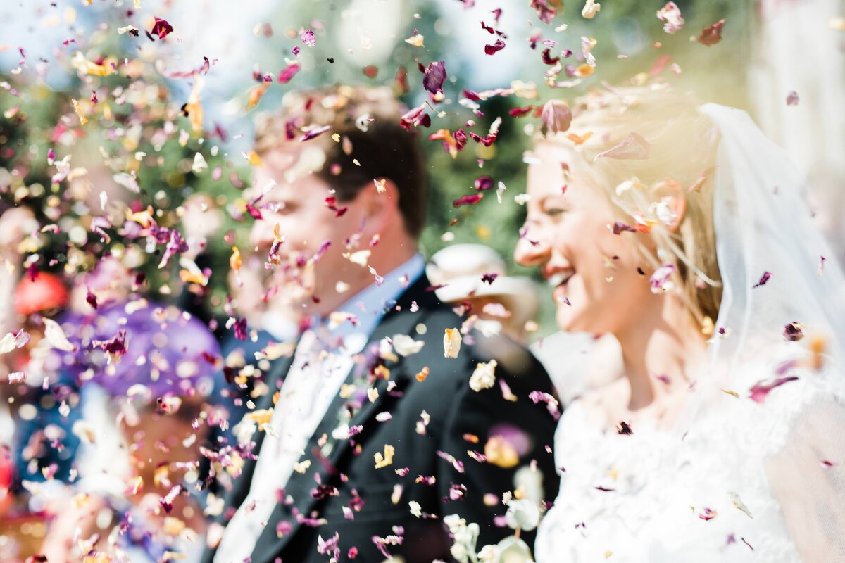 Creative confetti shot of a real Bride and Groom; blurry bokeh effect of colourful pink and yellow confetti.