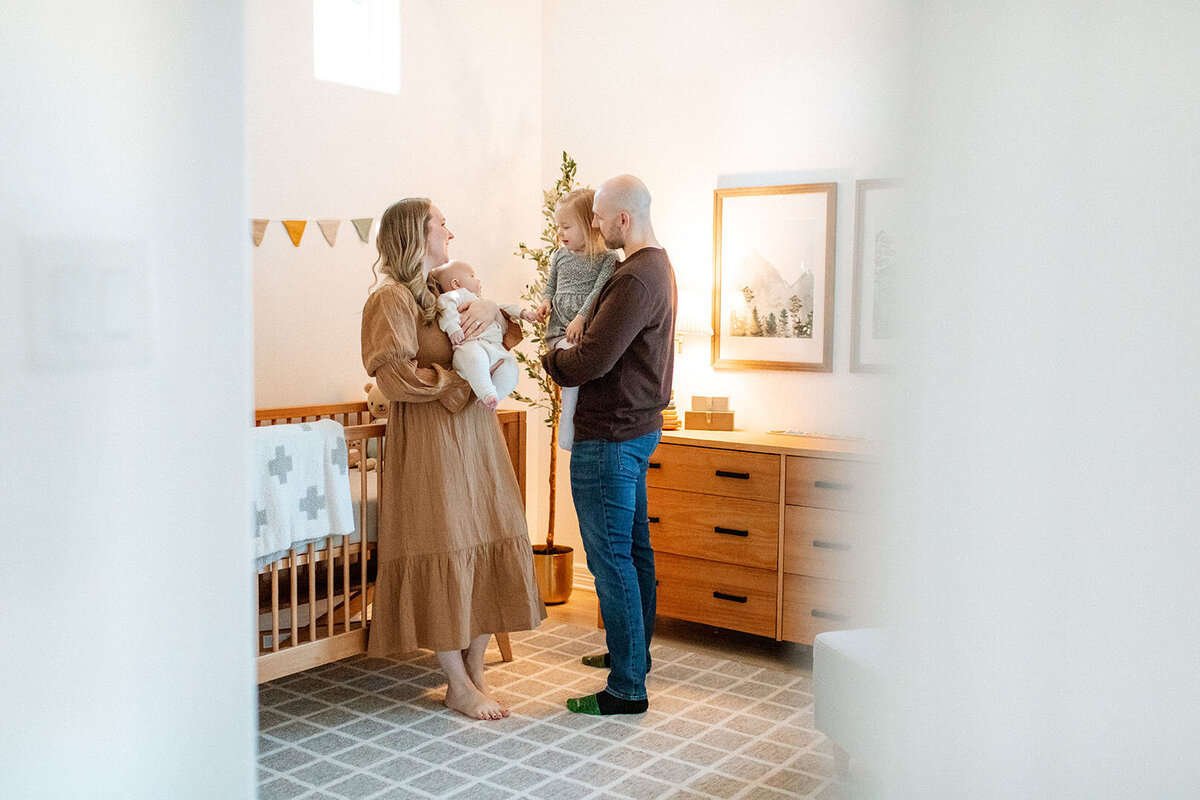 Family gathering in nursery with soft natural lighting - Sara James documents newborn family moments and nursery lifestyle photography during intimate home sessions in San Antonio Texas