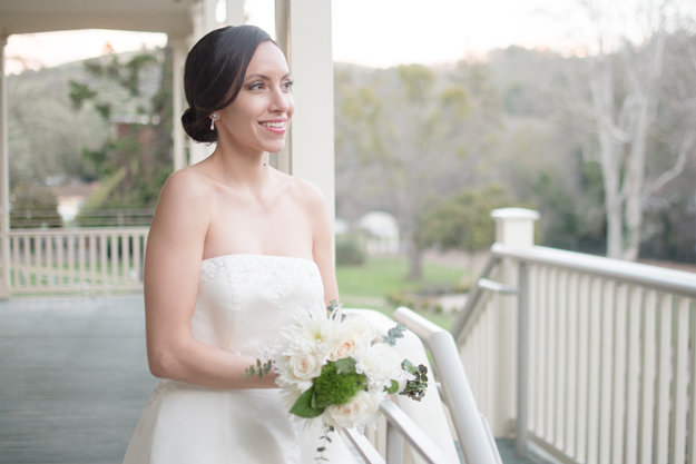 Bride with brown eyes and brown hair in updo white florals on a porch with classic bridal makeup for hazel eyes