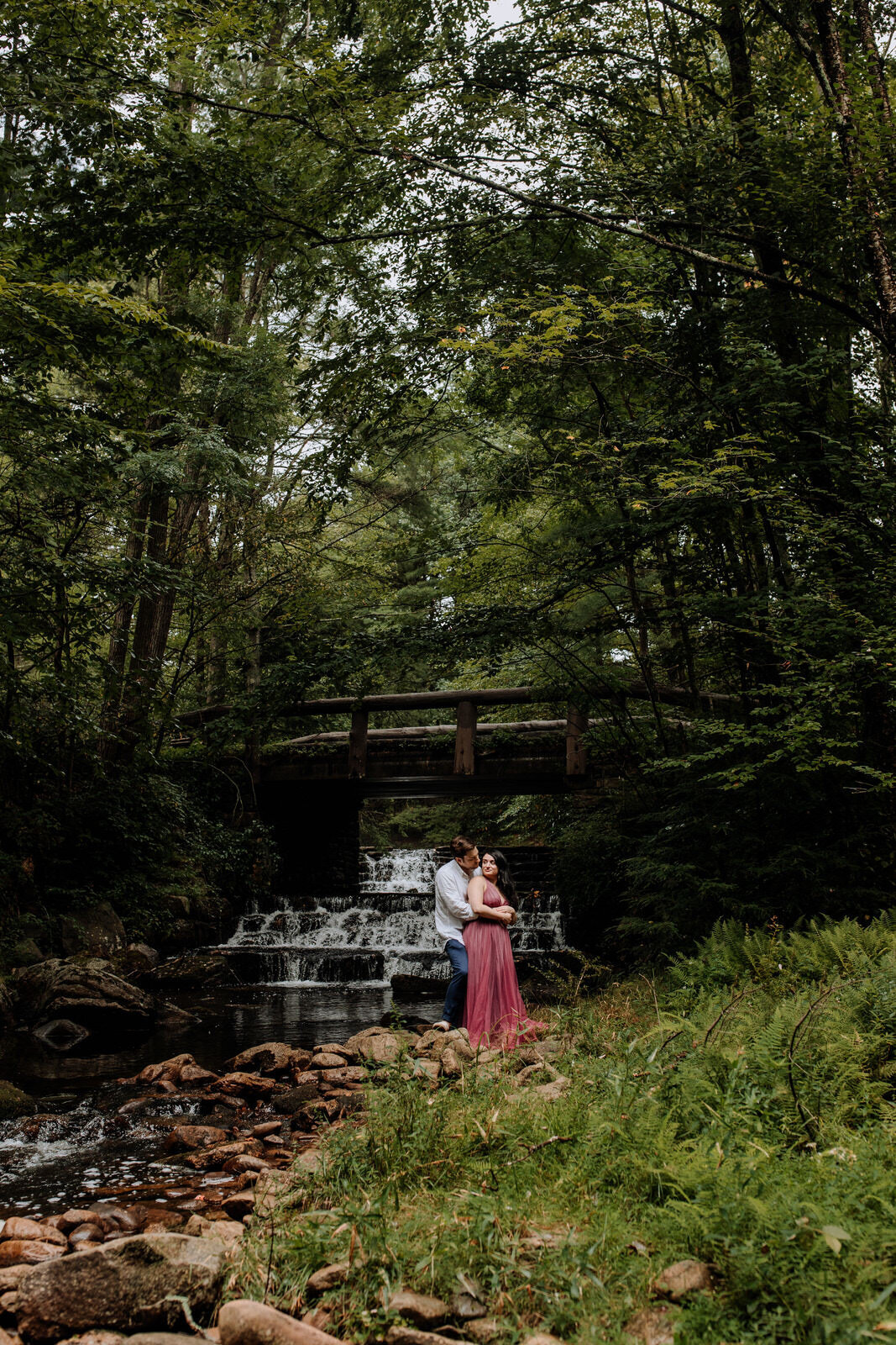 Bride and groom holding hands looking at each other while standing in front of rolling hills with the sunlight coming down on them