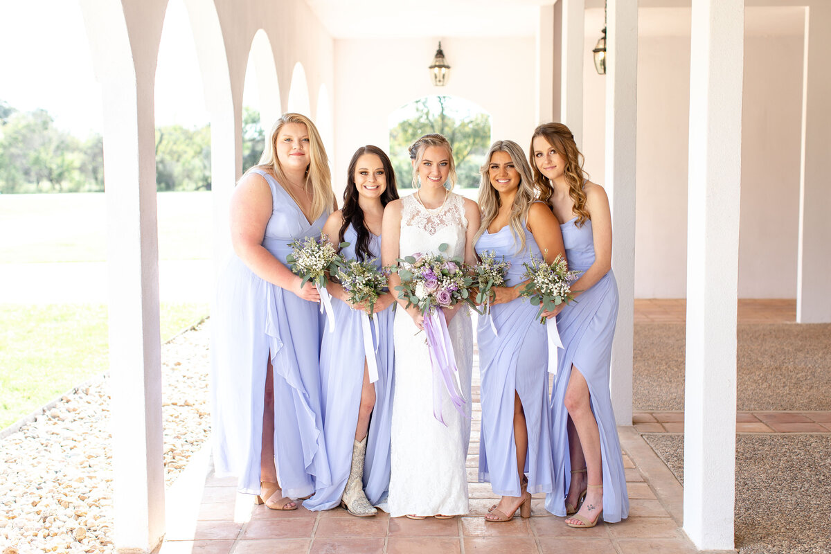 bride and four bridesmaids in lavender dresses stand in arches at La Dolce Vita in New Braunfels Texas
