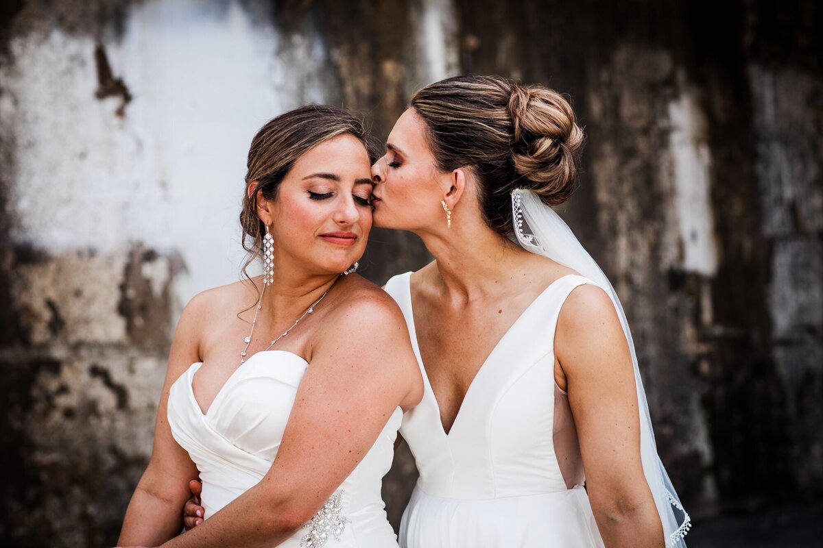 A bride kisses her bride before an Ignite Glass Studios wedding.