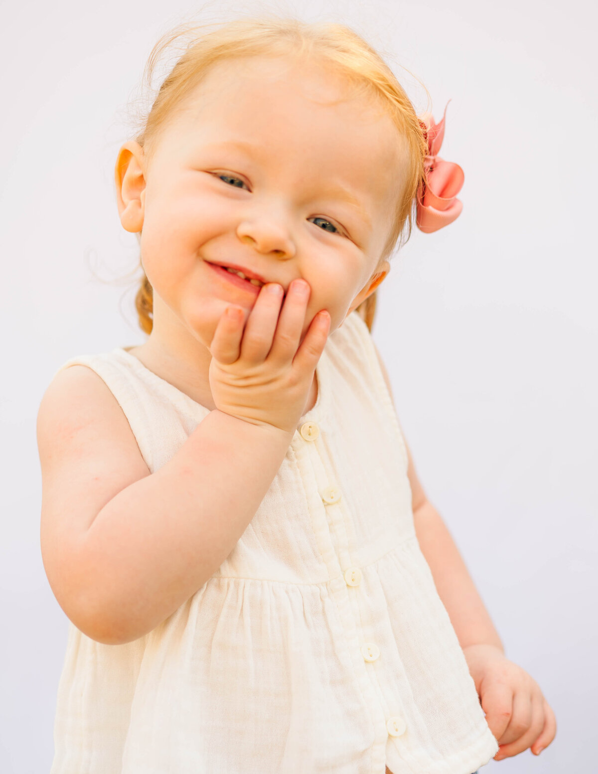 Close-up of smiling toddler girl, white background fine art school photo