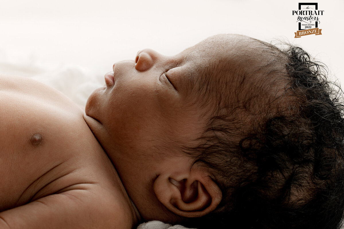 Newborn Photographer, a baby lays sleeping on white linens