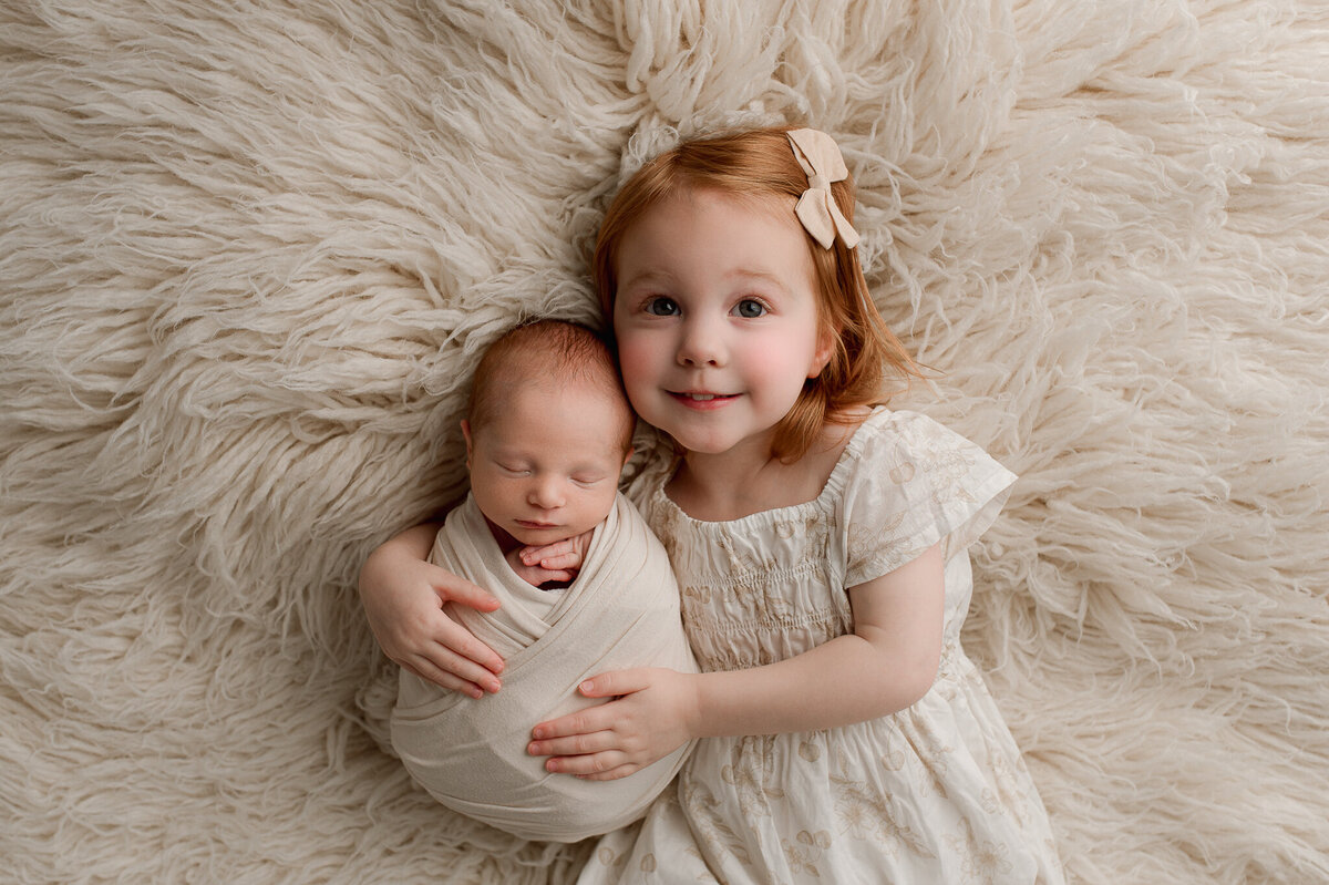 Sister and newborn session in studio cream swaddle