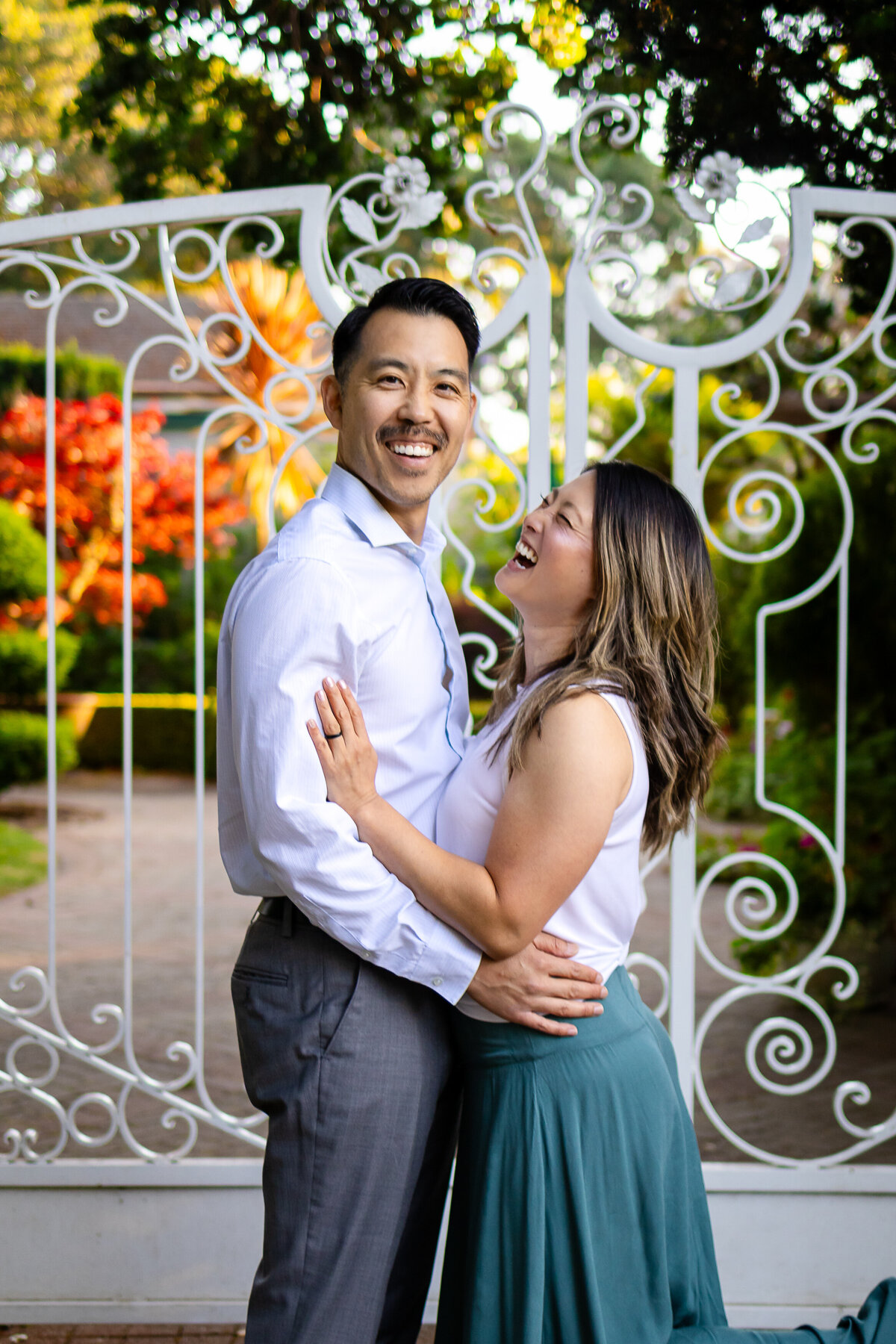 Romantic couple laughing in front of a decorative white gate