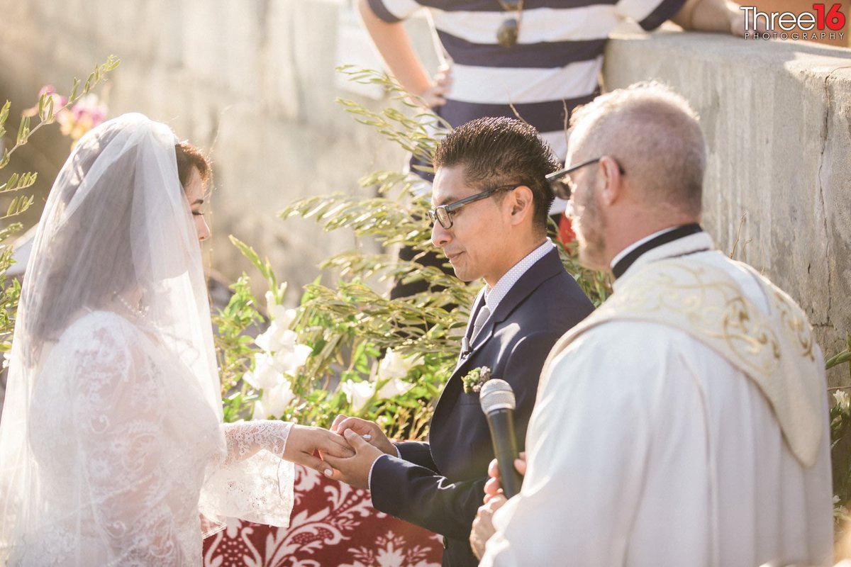 Groom placing the ring on his Brides finger