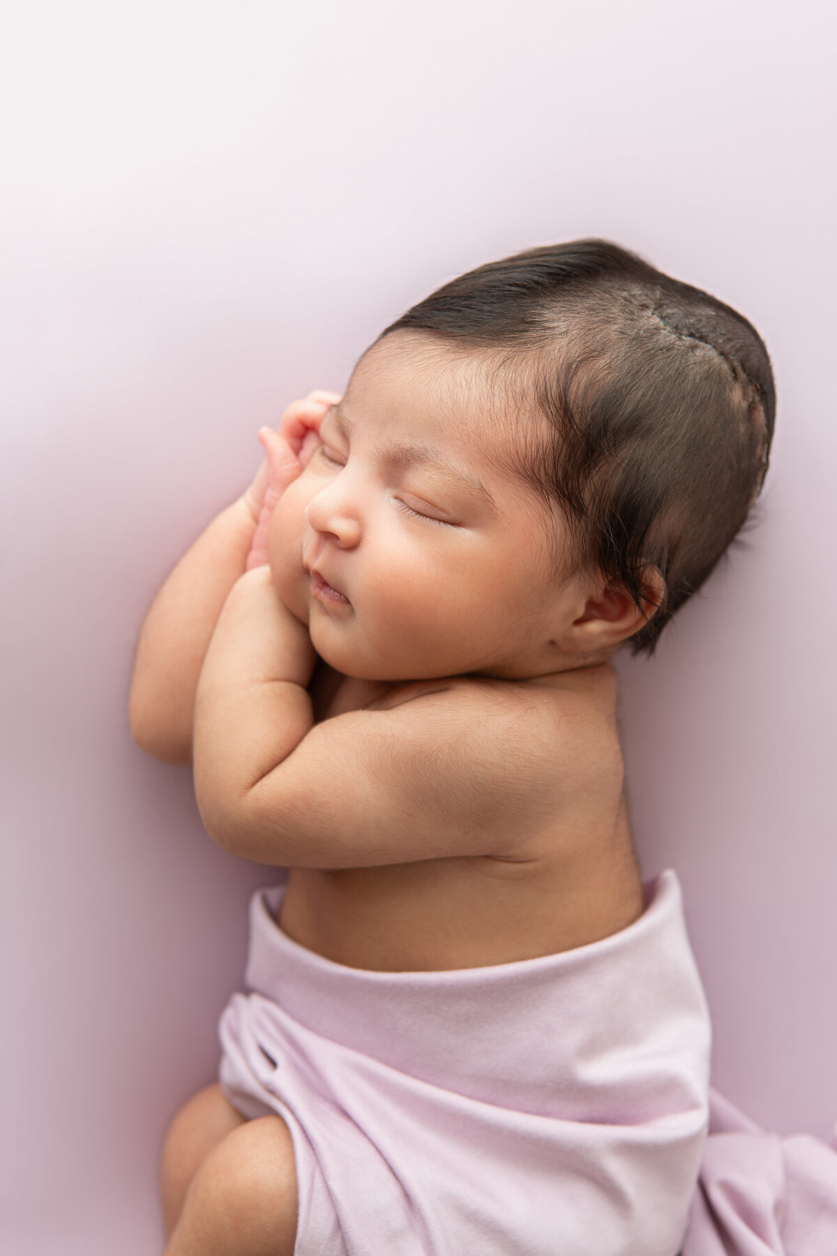 Posed newborn on a lilac backdrop