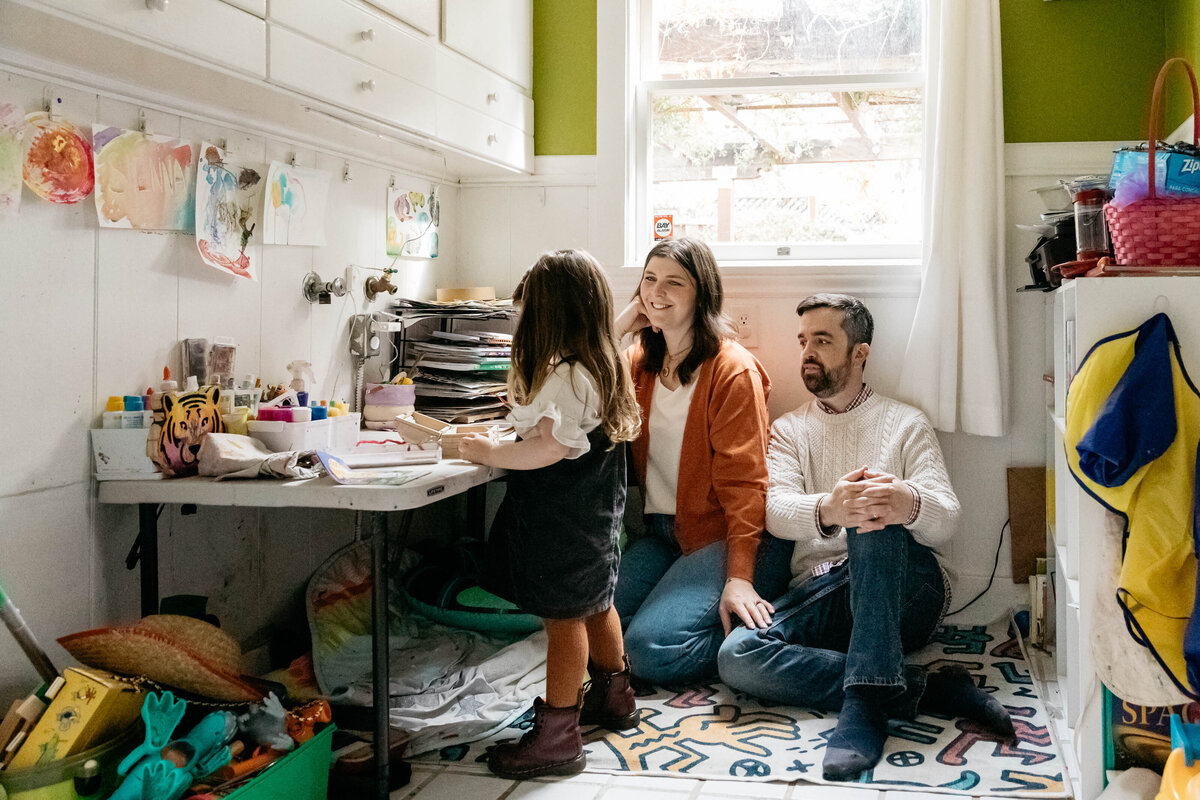 Mom and dad are watching their toddler daughter draw from the art room of their home.