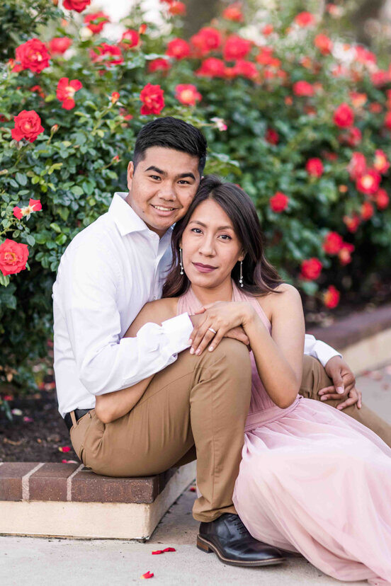 engaged couple sitting in rose garden balboa park