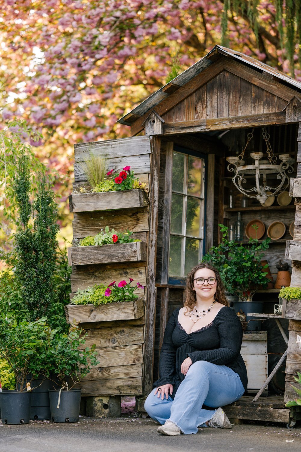 redmond high school senior sitting under cherry blossoms at garden center