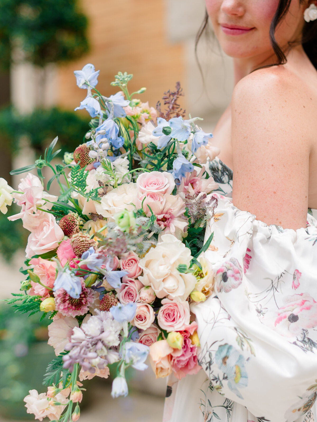 Close-up of a romantic bridal bouquet featuring blush roses, pastel delphinium, and whimsical wildflowers, captured by Philadelphia Fine Art Wedding Photographer Elizabeth Kane at Cairnwood Estate. The soft floral palette pairs beautifully with the bride’s off-the-shoulder botanical gown, evoking timeless garden wedding elegance.