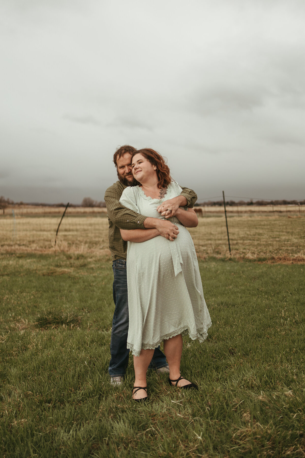 pregnant mom being loved on by her partner hugging her from behind during lifestyle maternity session with alexis adkins photography in longmont colorado