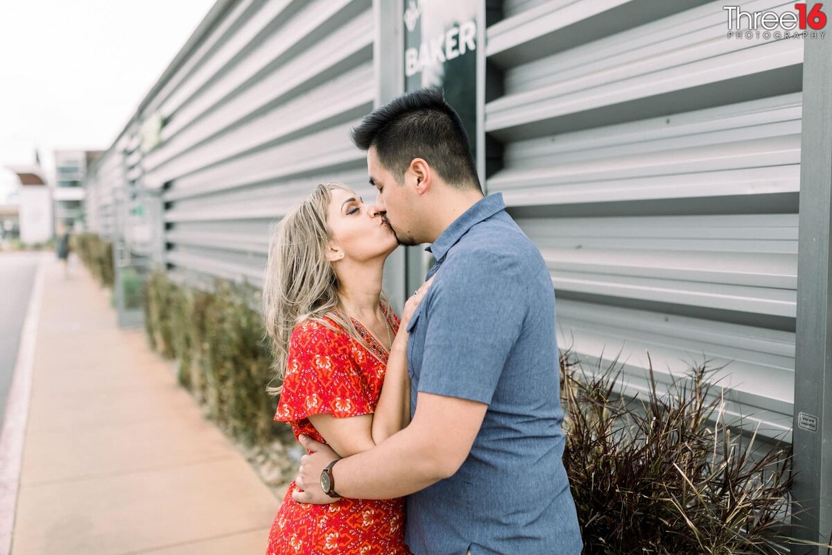 Engaged couple share a romantic kiss while visiting The CAMP in Costa Mesa