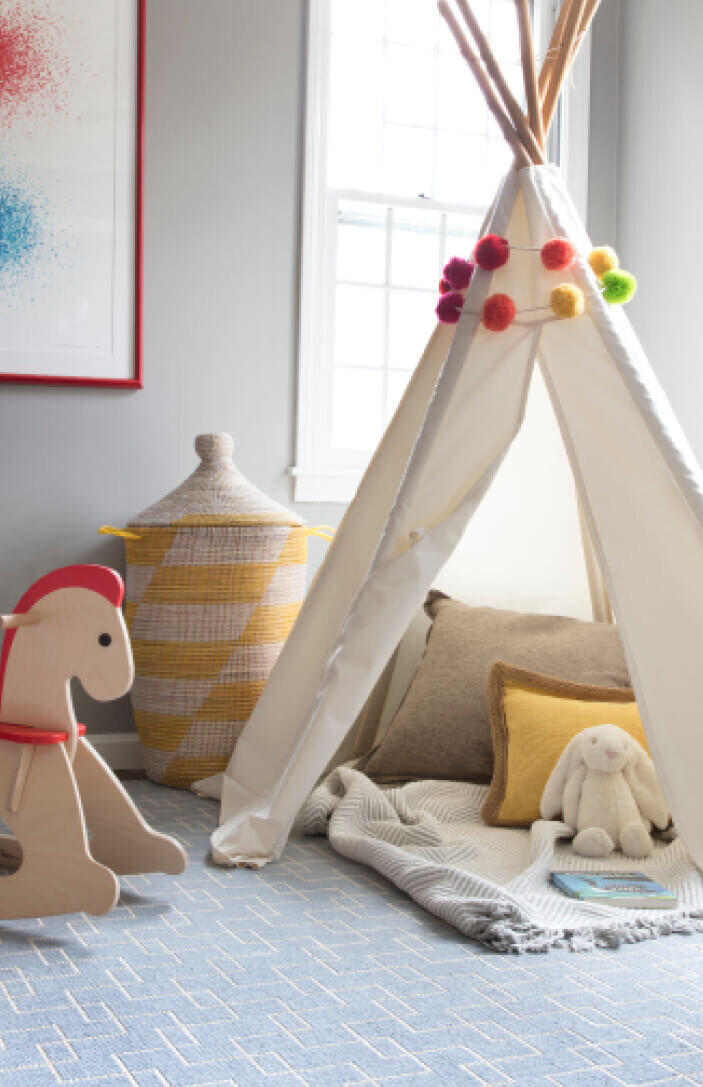 Kids playroom design in Westwood, MA features a cozy teepee, a light blue area rug, and a playful yet functional space designed for creativity and fun.