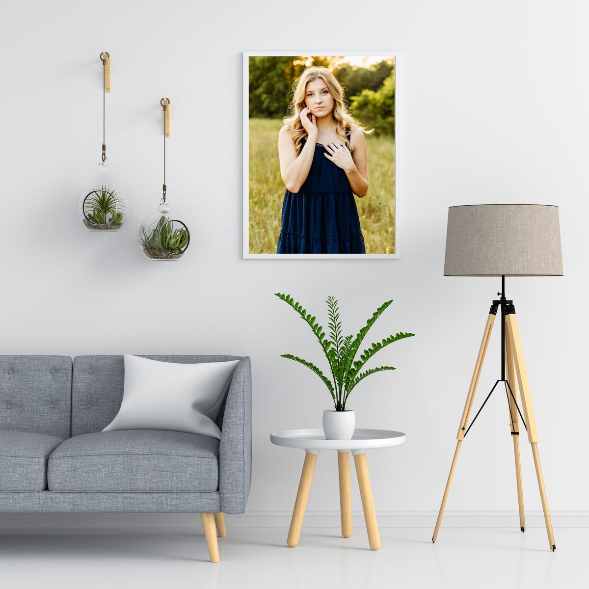 simple living room with plants and a framed senior portrait hanging on the wall