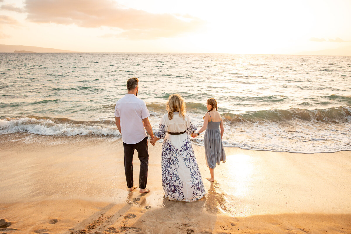 Maui Family Photographers capture family standing beachside holding hands during family beach photos