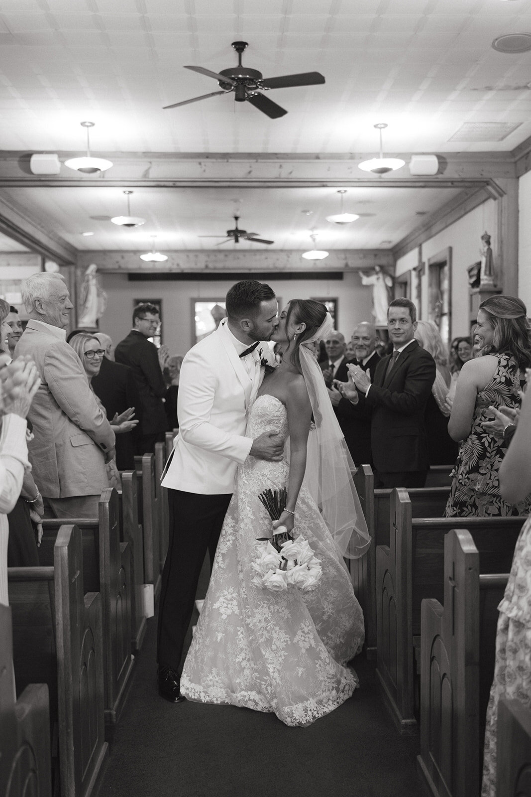 Bride and groom share a kiss while walking back down the aisle after their ceremony in Highlands, North Carolina, surrounded by cheering guests.