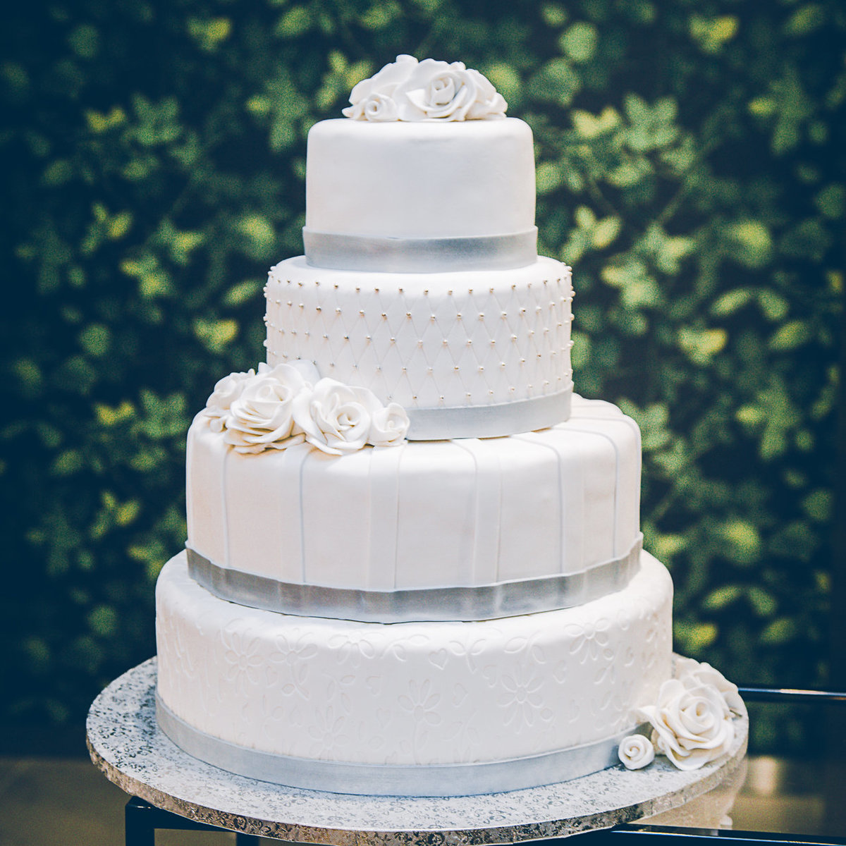 Bruidstaart van Berg's Bakery met zilveren details en witte rozen.
