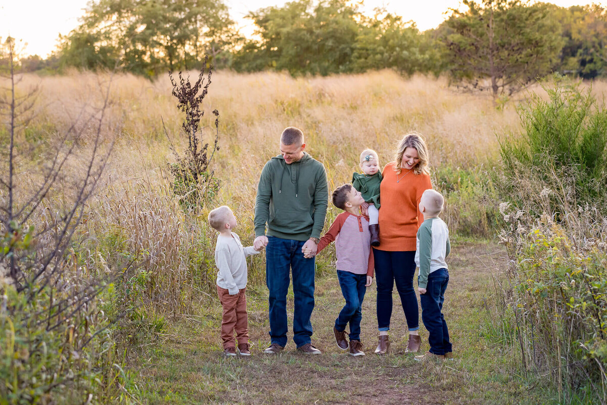 A family of six posing in a field at sunset at their Haymarket family photography session.