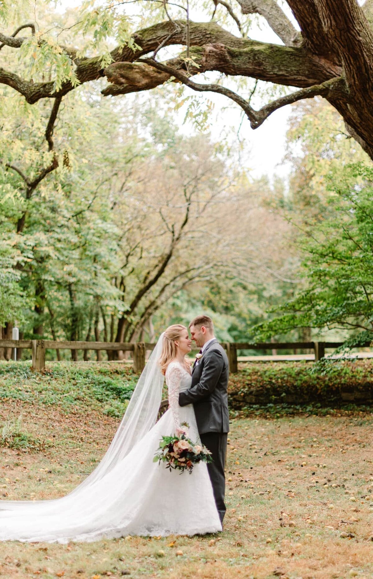 Bride and groom embrace under tree at Woodend Sanctuary wedding