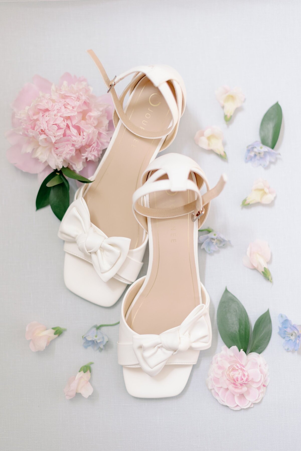 white bridal shoes surrounded by colorful flowers