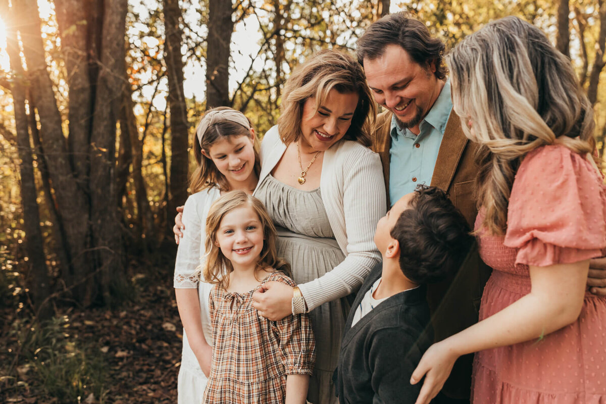 beautifully styled family loving on each other while youngest daughter smiles at the camera.