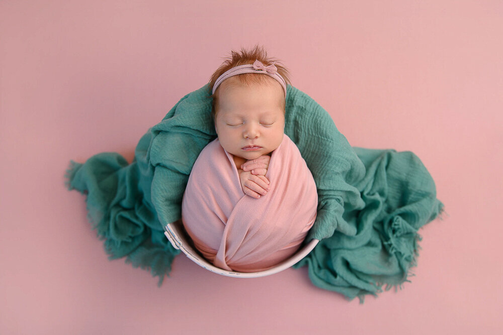 newborn girl wrapped in pink for her newborn photography session.